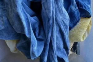 Deep blue indigo-dyed cloth hanging in soft folds, with pale yellow-green fabric showing at the edges.